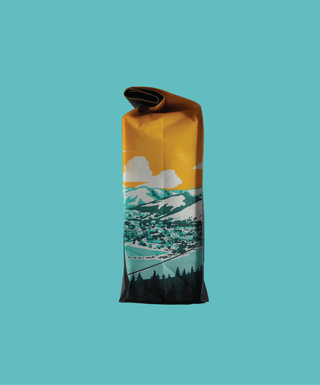 Yellow pouch with mountain graphics at bottom and a rolled top against a teal background
