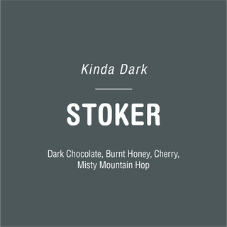 Kinda Dark Stoker coffee bag on dark teal background with large STOKER label and tasting notes Dark Chocolate Burnt Honey Cherry Misty Mountain Hop