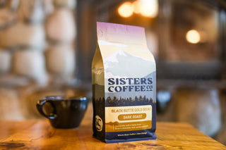 Sisters Coffee Black Butte Gold Decaf bag with mountain label on a wooden table