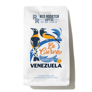 Hand holding a Venezuela La Curva coffee bag featuring vibrant bird illustration and Red Rooster Coffee branding