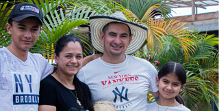 Group of four people posing outdoors among tropical plants smiling at the camera