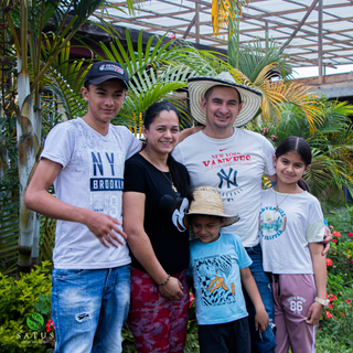 Family of five posing together among tropical plants on a coffee farm