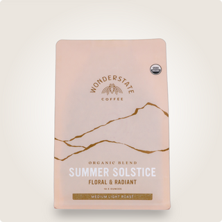 Close up of pink Organic Summer Solstice coffee packaging with decorative lines and USDA Organic badge.
