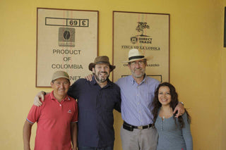 Four people pose in front of framed signs at Finca Villa Loyola farm.