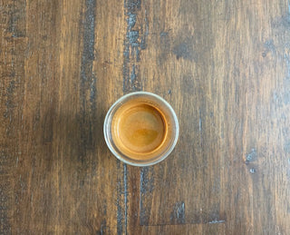 Top view of a single espresso shot in a glass on a wooden table