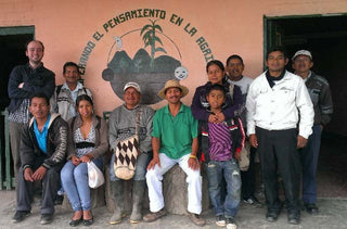Group photo of Fondo Paez cooperative farmers posing in front of a mural.