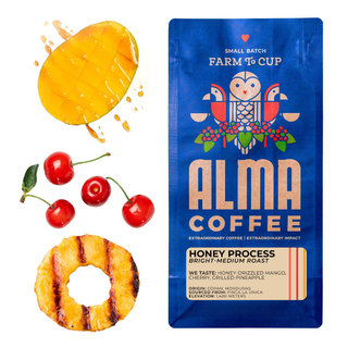 Mango slices cherries and a grilled pineapple ring beside a blue Alma Coffee Honey Process bag