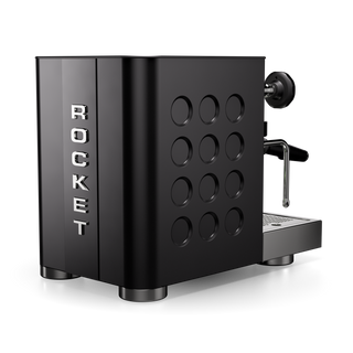 Side view of the Rocket Appartamento TCA espresso machine with a black metal body, a protruding portafilter, and round side panel holes.