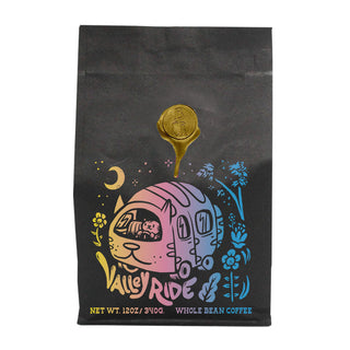 Valley Ride whole bean coffee bag with a colorful pastel illustration of a van and flowers on a black bag